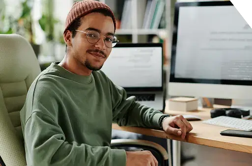 Man-smiling-at-desk-with-computers