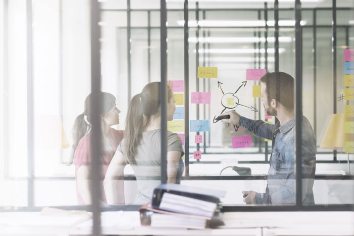 Man drawing company strategy on a glass board