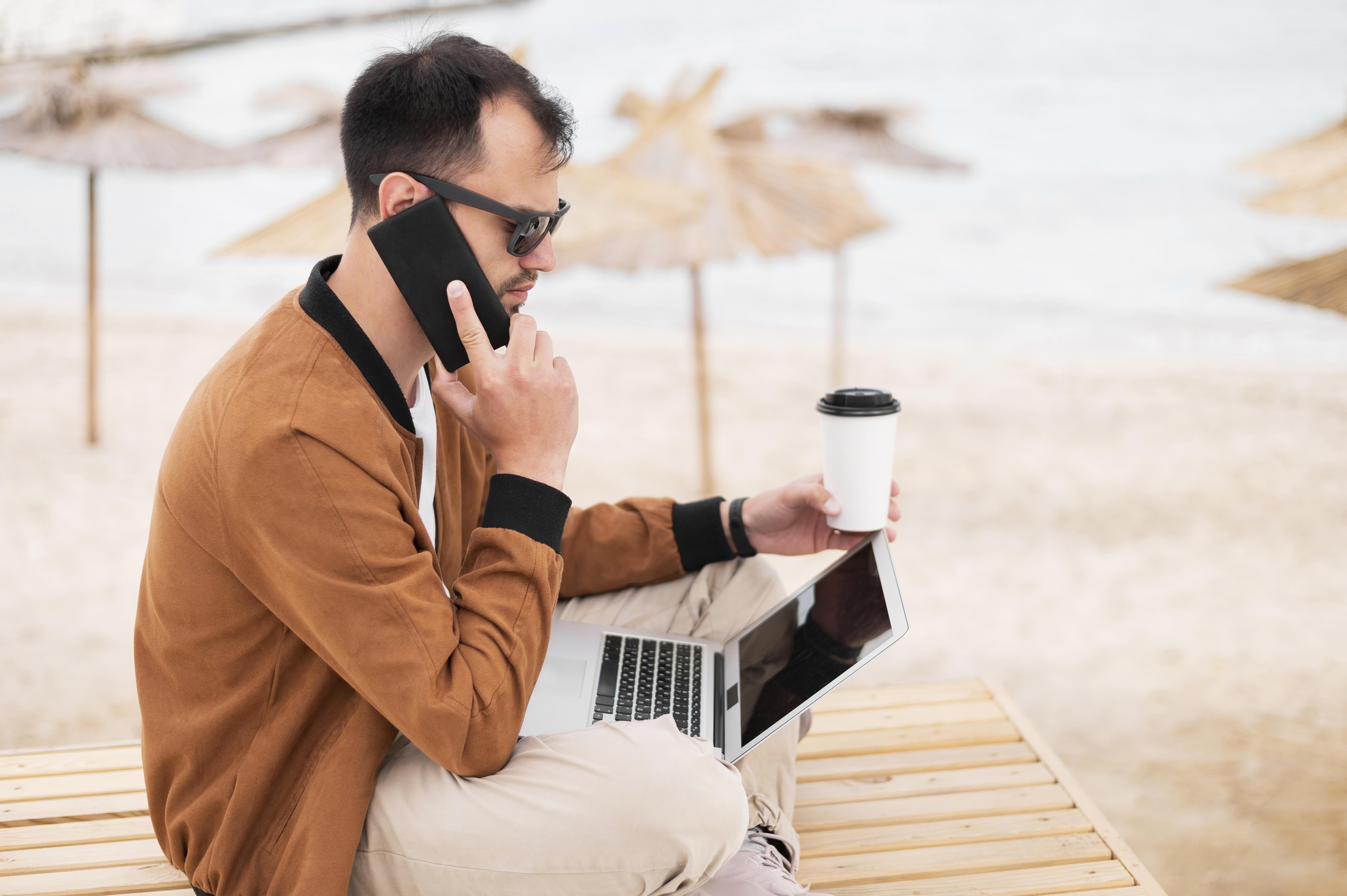 side-view-man-beach-working-while-having-coffee